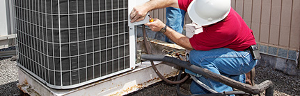 Two workers on the roof of a building working on the air conditi